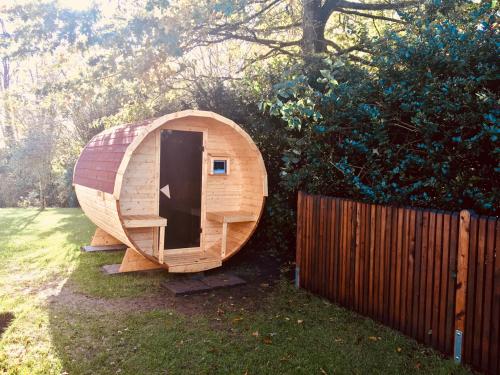 a small wooden sauna in a yard next to a fence at Moorblick! Große Dachwohnung mit Kamin und Sauna in Leck