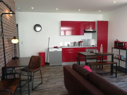 a living room with a couch and a kitchen with red cabinets at Cocoon Bugiste : travail, sport ou détente in Hauteville-Lompnes