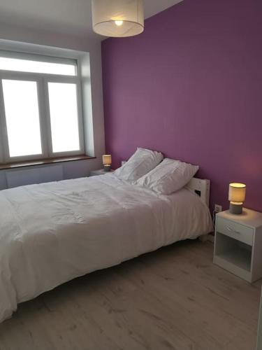 - une chambre avec un lit blanc et un mur violet dans l'établissement Cocoon Bugiste : travail, sport ou détente, à Hauteville-Lompnes