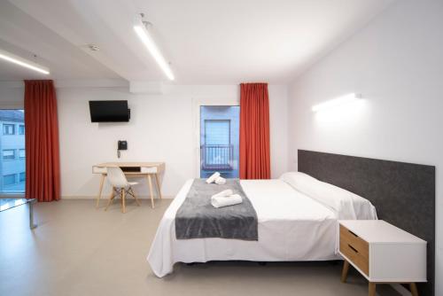 Dormitorio con cama, escritorio y TV en Epsilon Alcañiz Hotel, en Alcañiz