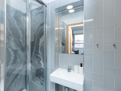 Un baño con ducha, lavabo y espejo. en New Stylish Studio Flat near Woolwich tube, en Woolwich