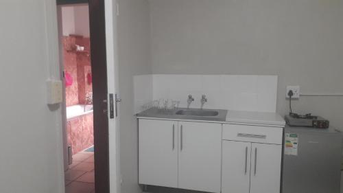 Una cocina blanca con fregadero y refrigerador. en 3 Lavenders, en Bloemfontein