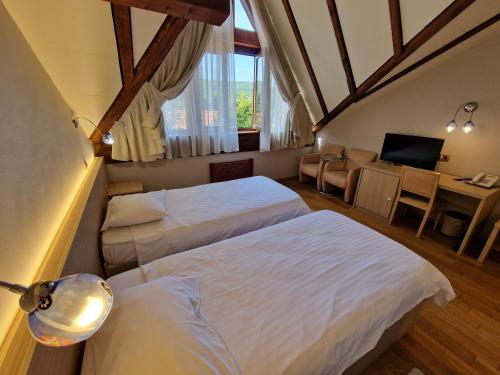 a hotel room with two beds and a desk and a room at Hotel Sunny Hill in Cluj-Napoca