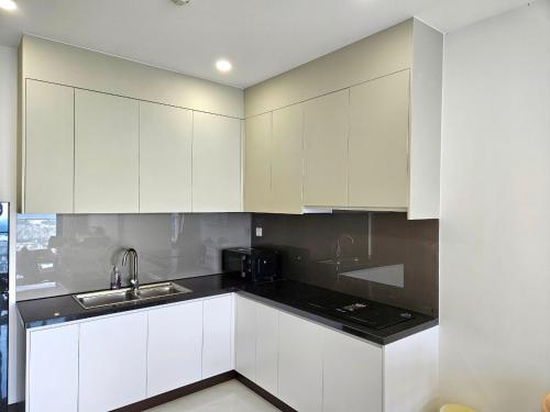 a kitchen with white cabinets and a black counter top at C Sky View: 2 BR Apartment Free GYM & POOL in Thu Dau Mot