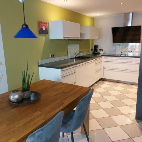 a kitchen with a wooden table and blue chairs at le cadeau in Wincheringen