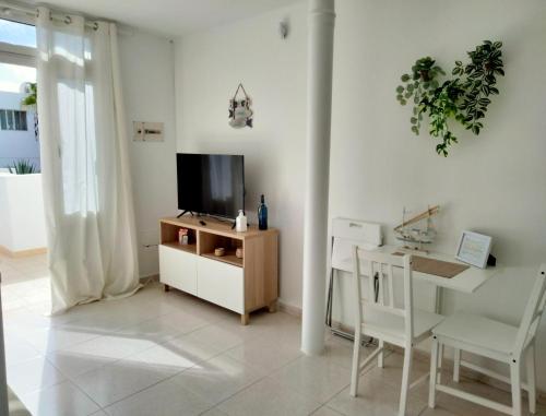 uma sala de estar com televisão e uma mesa e cadeira em Mirador de Sotavento apartment 103 em Costa Calma