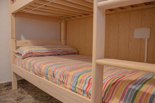 a wooden bunk bed with a striped bedspread on it at Casa Llurgo in Deltebre