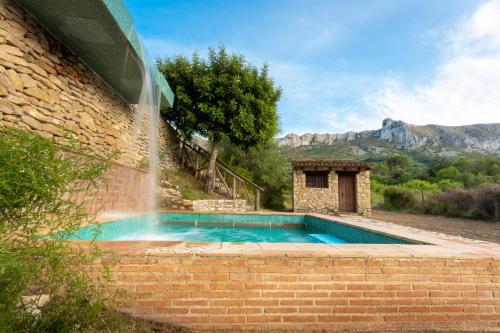 una piscina con fontana che esce da un edificio di Casa Rural Ca Ferminet & Cabañas de montaña La Garriga a Benisili