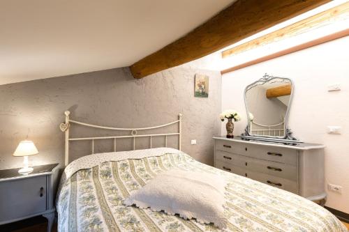 een slaapkamer met een bed, een dressoir en een spiegel bij B&B Corte del Mincio in Monzambano