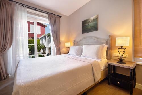 a bedroom with a large white bed and a window at Bramasole Alaçatı Butik Hotel in Alacati