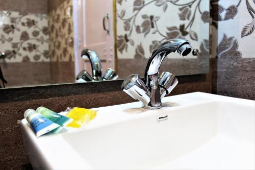 a bathroom sink with a chrome faucet and toothpaste at Hotel Nirvana Hills With Balcony Rooms And Open Terrace in Manāli