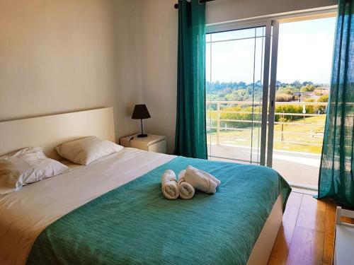 a bedroom with a bed with two pairs of slippers at Zambujal Sun in Sesimbra