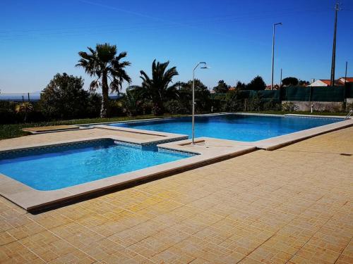 una grande piscina con acqua azzurra e palme di Zambujal Sun a Sesimbra