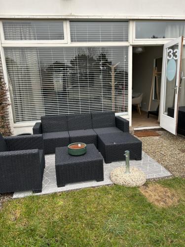 a patio with a black couch and a table at Amsterdam Beach Apartment 33, Private Garden in Zandvoort