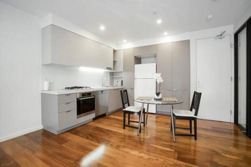 cocina con armarios blancos, mesa y sillas en Beachfront Bliss: Luxury Living en Geelong