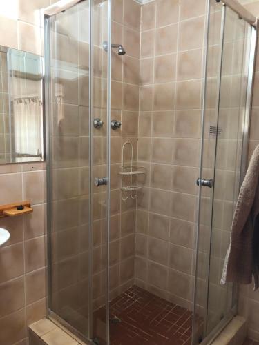 a shower with a glass door in a bathroom at Cheerio Trout Fishing & Holiday Resort in Haenertsburg
