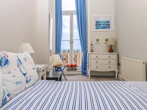 1 dormitorio con 1 cama y una ventana con cortinas azules en The Old Spy Headquarters, en Folkestone