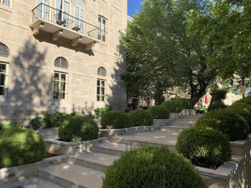 a courtyard in front of a building with bushes at Grand Kadri Hotel - History Marked by Cristal Lebanon in Zahlé