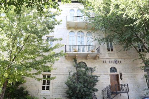 an old stone building with a balcony and trees at Grand Kadri Hotel - History Marked by Cristal Lebanon in Zahlé