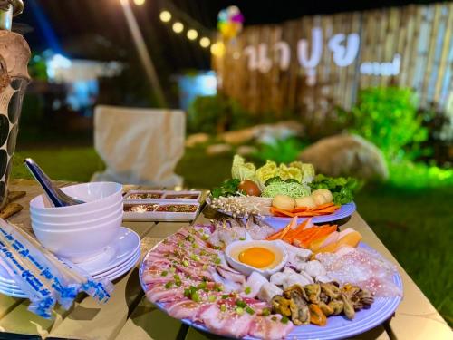 a table with two plates of food on it at นาปุย คันทรีโฮม Napui Countryhome 纳普乡村别墅 in Ban Huai Kaet