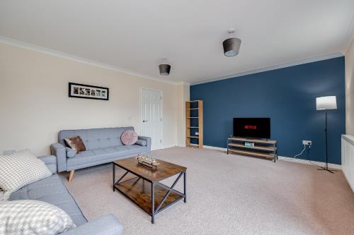 a living room with a couch and a tv at 3 Bed House, Sleeps 8 - Contractors, Relocators & Visitors, Parking, Garden, Wi-Fi & Foosball table in Bedford