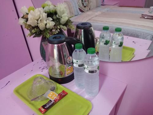 a table with bottles of water and a vase with flowers at Pattaya inn By Thai Smile in Pattaya