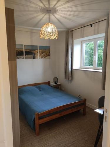 - une chambre avec un lit bleu et un lustre dans l'établissement Le Relais des Cigognes, à Marlieux