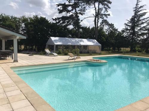 a swimming pool with two chairs and a house at Le Relais des Cigognes in Marlieux