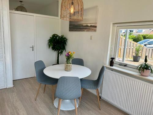 een eetkamer met een witte tafel en stoelen bij Amsterdam Beach Apartment 17, incl Parking + Garden in Zandvoort