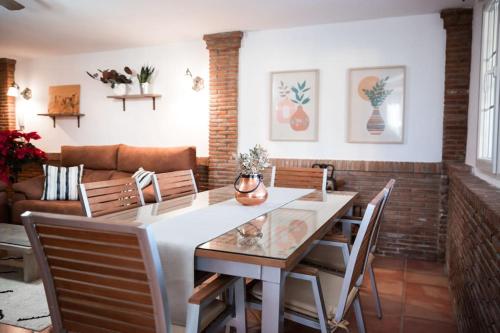 een eetkamer met een tafel en stoelen en een bank bij Casa espaciosa cerca de Monachil in La Zubia