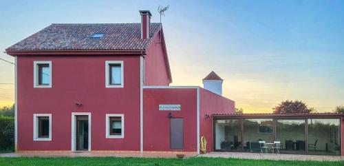 une grande maison rouge avec une grande fenêtre en verre dans l'établissement AG Casa Bértoa con jardín y comedor exterior x8, à Queo de Abaixo