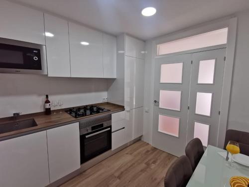 a kitchen with white cabinets and a table and a door at Bonito Ático in Terrassa