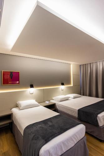a hotel room with two beds and a window at Hotel São Mateus in São Mateus do Sul