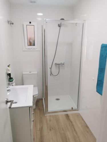 a white bathroom with a shower and a sink at Ático in Terrassa