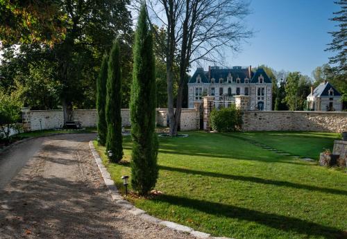 un parc avec des cyprès devant un bâtiment dans l'établissement Le Clocher de la Duchesse, à Bonnelles