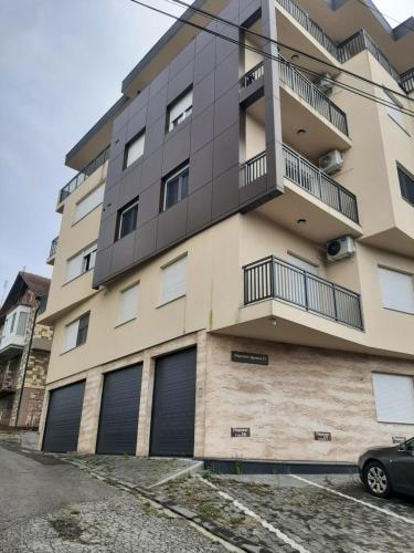 un edificio de apartamentos con puertas de garaje y un coche aparcado delante en Zvezdica en Banja Koviljača