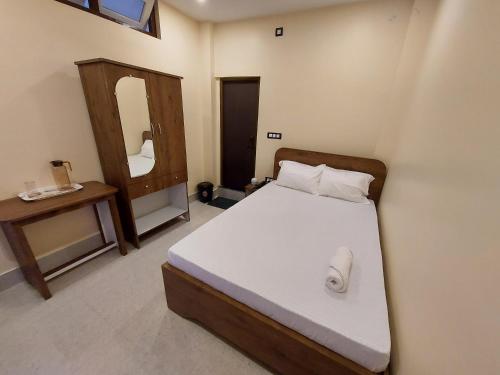 a small bedroom with a bed and a mirror at Hotel Hari Gayatri Regent in Guwahati