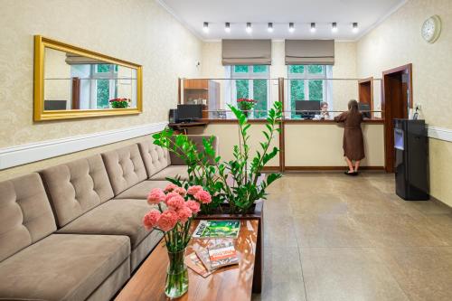 a lobby with a couch and a woman at a counter at Hotel Maximum in Krakow