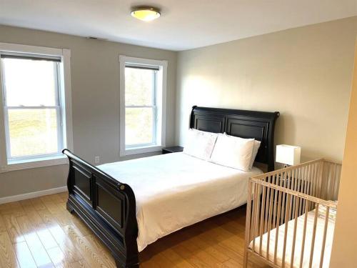 a bedroom with a black bed with two windows at Two DC Rowhouses Large Groups Sleeps 21 in Washington