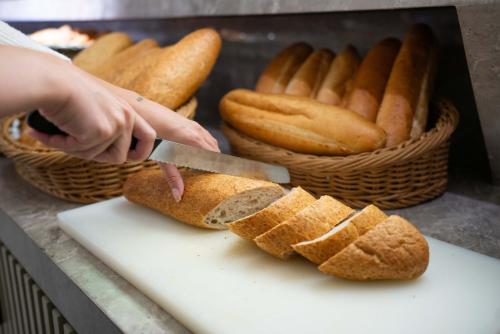 a person cutting bread on a cutting board with a knife at Four Sides Taksim Lion Hotel&Spa in Istanbul