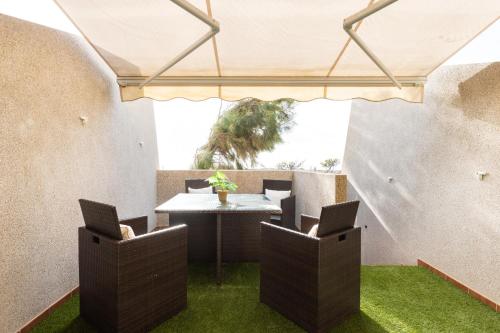 une terrasse avec une table, des chaises et de la pelouse. dans l'établissement Family Sea View Townhouse, à El Médano