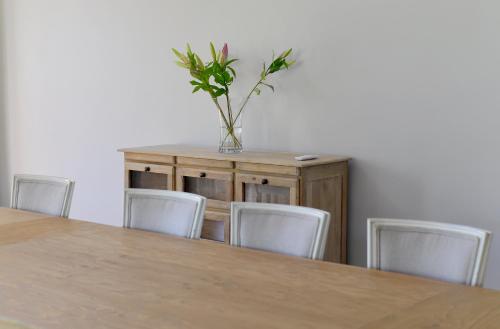a table with chairs and a vase with a plant at Fransvliet Guest House in Franschhoek