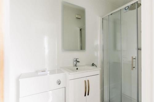 a white bathroom with a sink and a shower at Upper Cliff Studio in Portland
