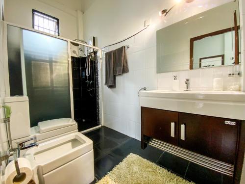 a bathroom with a toilet and a sink and a mirror at Jas - Sri Lankan Villa in Polgasowita