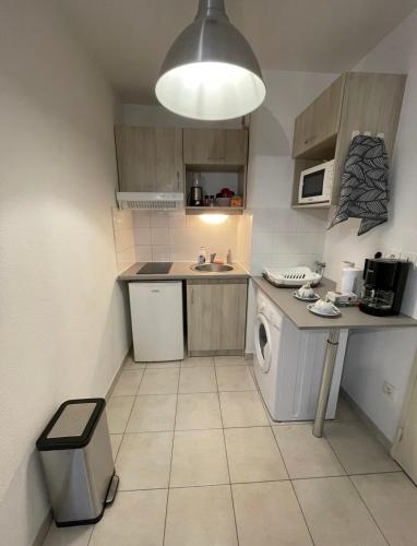 une petite cuisine avec un lave-linge et un sèche-linge. dans l'établissement Appartement avec place de parking et piscine, à Villefranche-sur-Saône