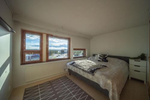a bedroom with a large bed and two windows at Arctic Penthouse in Rovaniemi