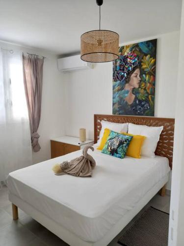 ein Schlafzimmer mit einem Bett und einem Gemälde an der Wand in der Unterkunft La casa tropicale in Le François