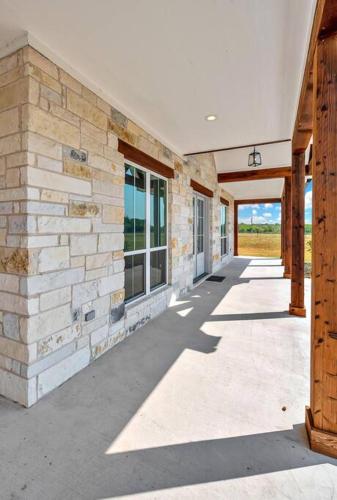 a building with a stone wall and a walkway at New Luxury Texas Farmhouse in Bellmead