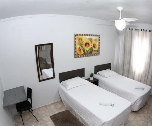 Cette chambre comprend 2 lits et un miroir. dans l'établissement HOTEL JOINVILLENSE, à Joinville