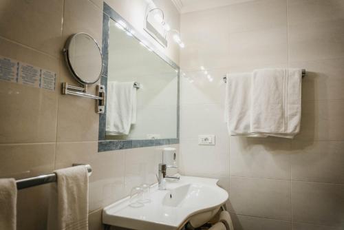 a bathroom with a sink and a mirror and towels at Dolomitenhotel Weisslahnbad in Tires
